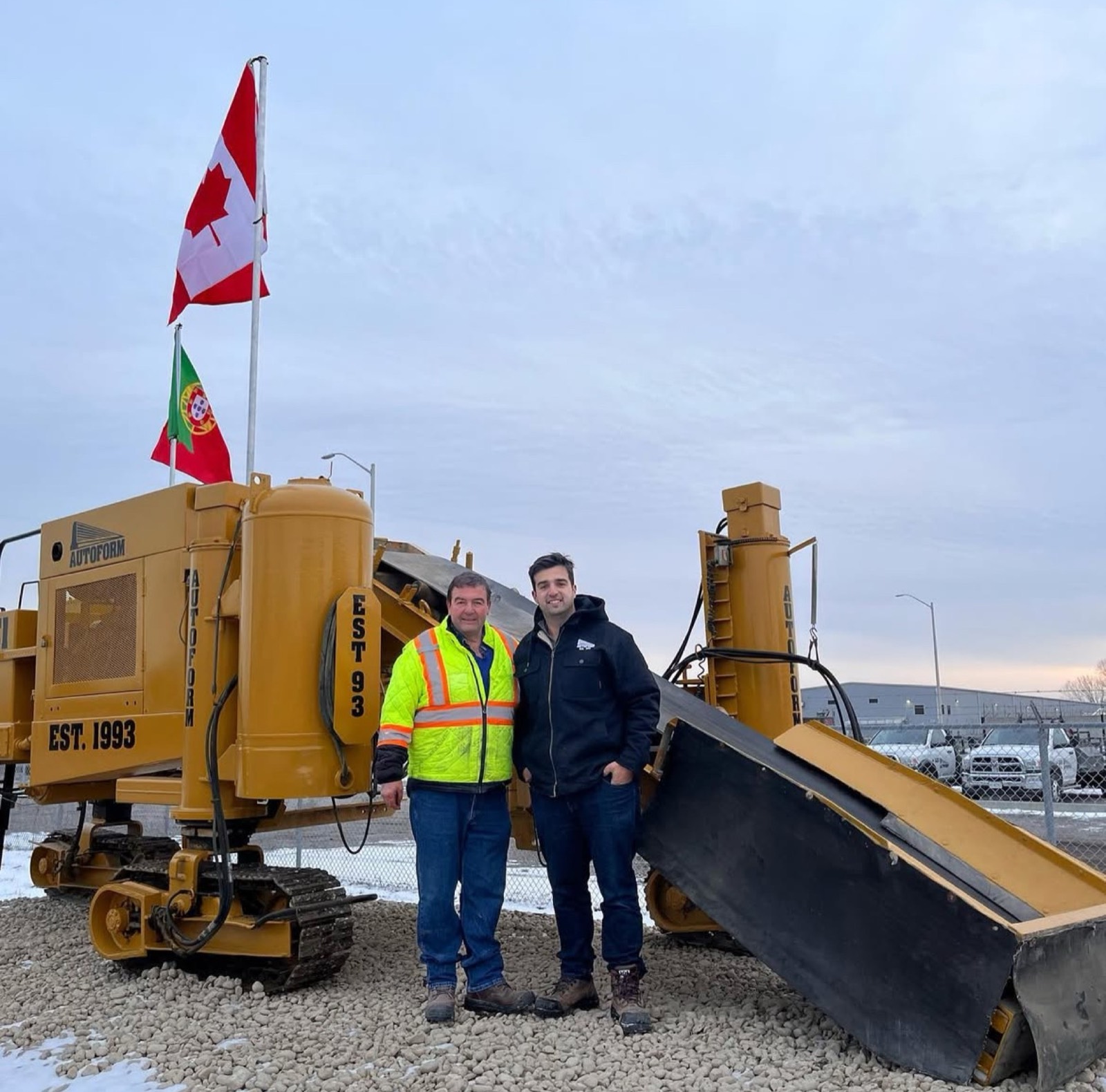 Two members of the Autoform family in front of an Autoform curb machine marked Est. 1993