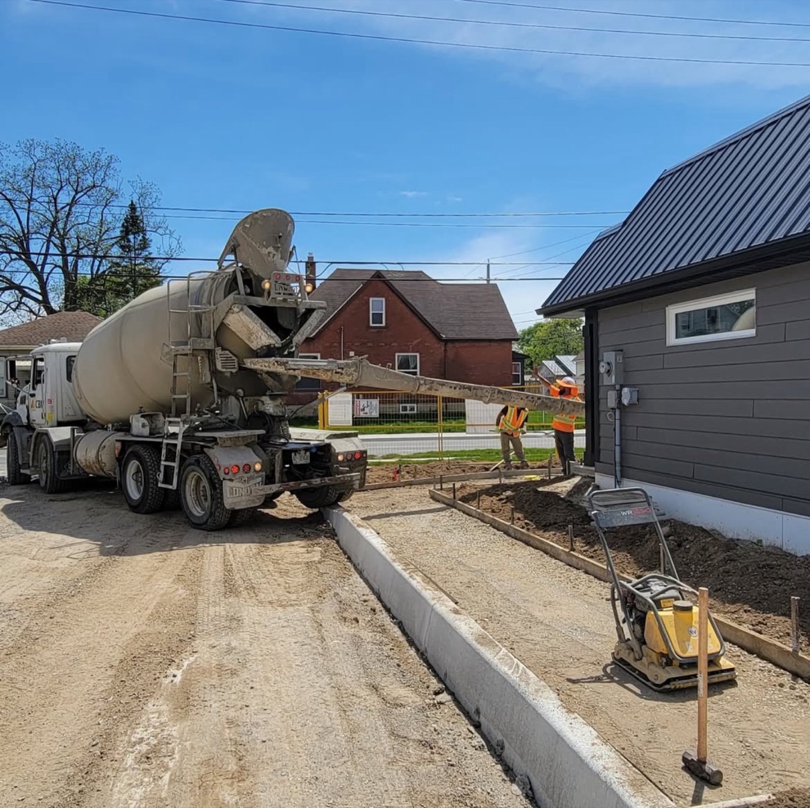 Ready-mix truck pouring a new sidewalk beside a fresh curb